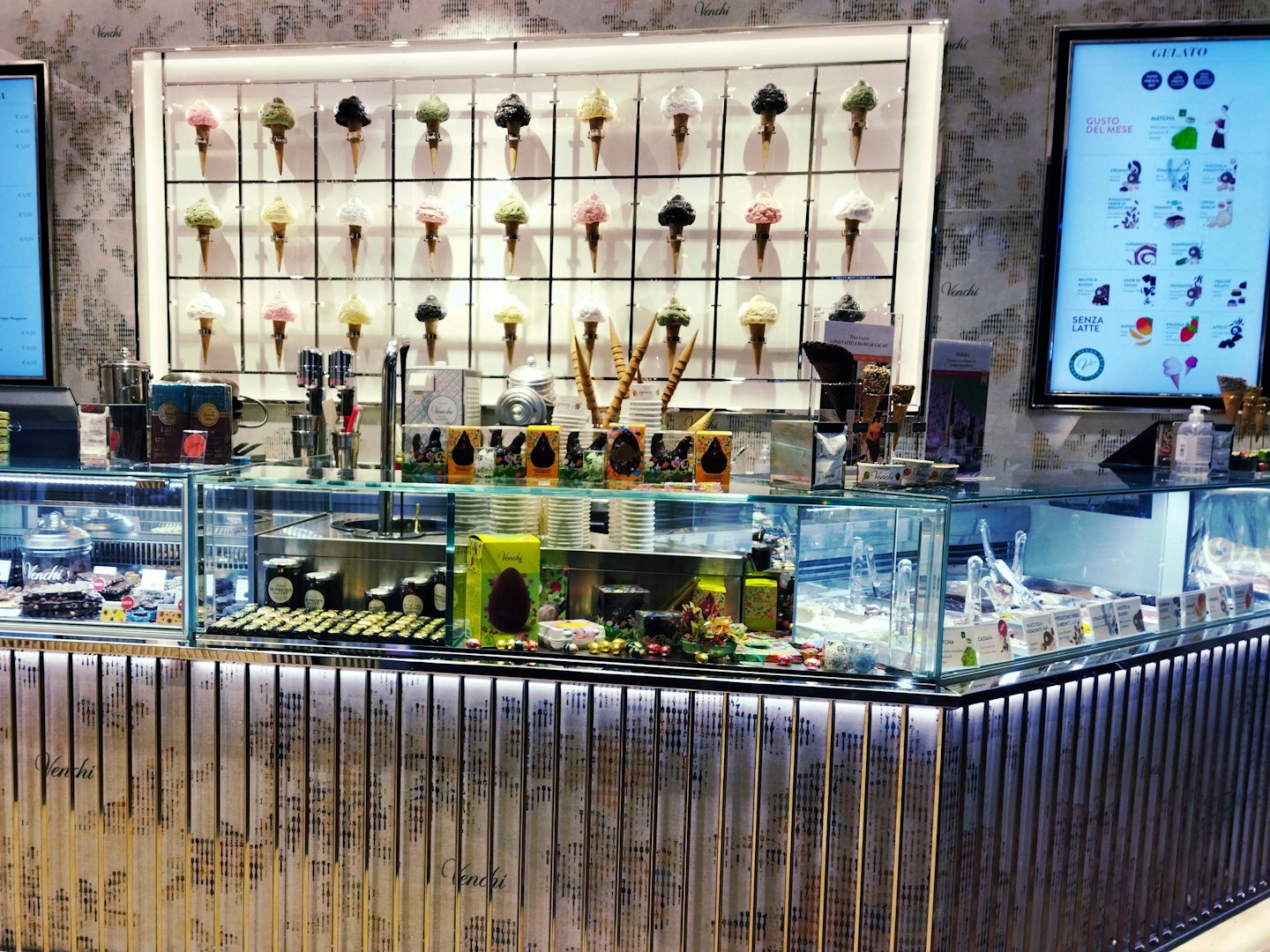 Modern Italian gelato shop featuring a chocolate display and menu screens.